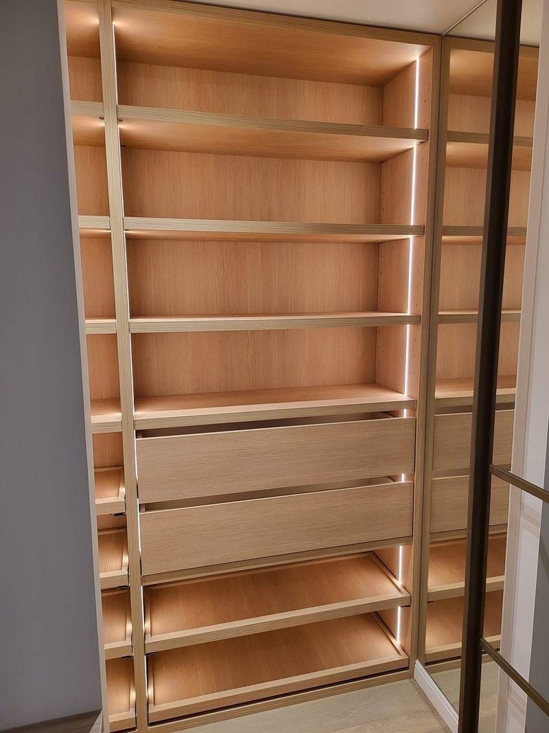 Colonne de dressing en bois clair avec étagères, deux tiroirs et tablettes à chaussures, éclairée par bandes LED verticales, miroir à droite